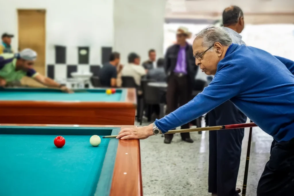 Senior man playing billiards with friends at a social club