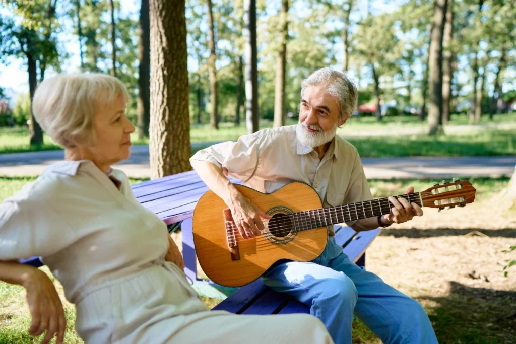 Senior man playing guitar for a woman in a forest setting