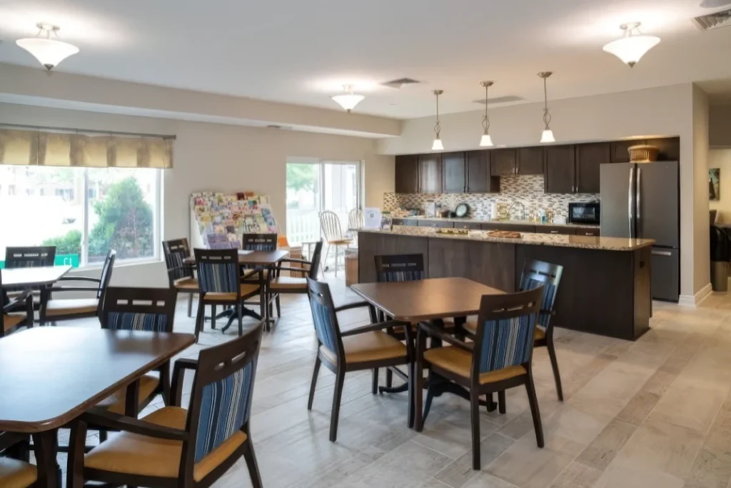 Dining and kitchen area with tables and chairs and a granite-topped island beside large windows