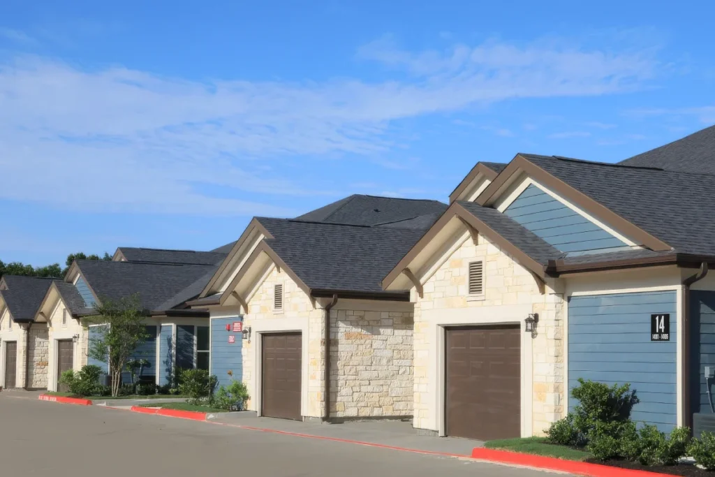 Row of single-story stone-and-siding homes with attached garages along a street
