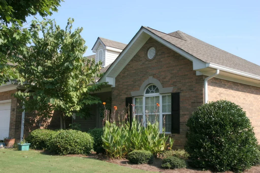 Brick home with an arched window, black shutters and trimmed shrubs