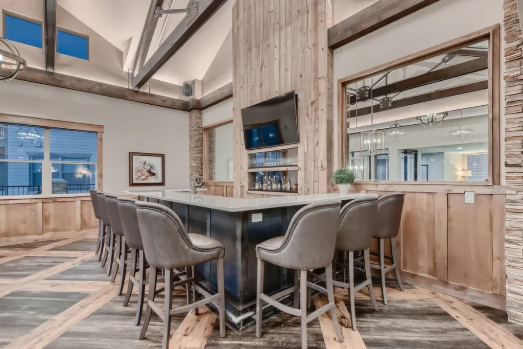 Clubroom with a bar counter with stools, a TV and wood-paneled walls