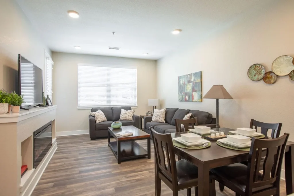 Living and dining area with a table set for four, a sofa and an electric fireplace