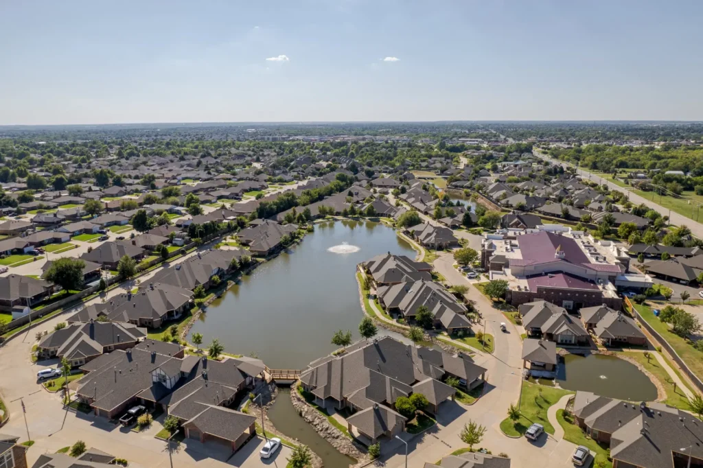 Aerial view of a large neighborhood of single-story homes around a pond