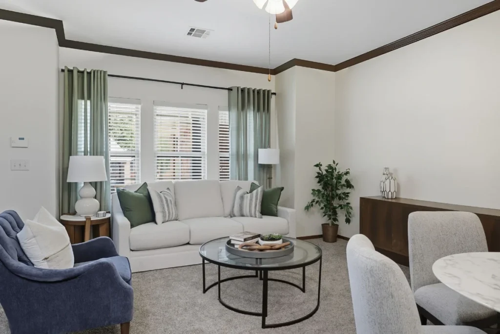 Living room with a white sofa, a blue armchair and a round coffee table beside a dining area