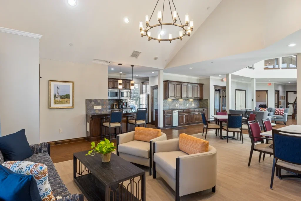 Lounge with a sofa, armchairs and a chandelier, with an open kitchen beyond