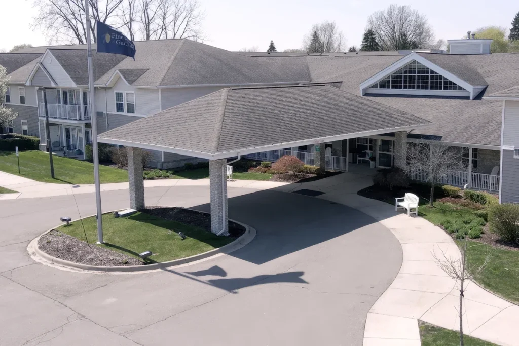 Aerial view of a covered drive-up entrance with a curved driveway and landscaping in front of a building