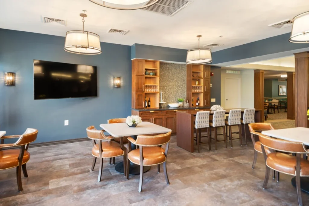Café-style room with blue walls, a wall-mounted TV, a bar counter with stools and small dining tables