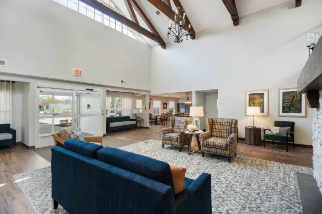 Bright lounge with a navy sofa, armchairs and exposed wood beams, with glass doors at the side