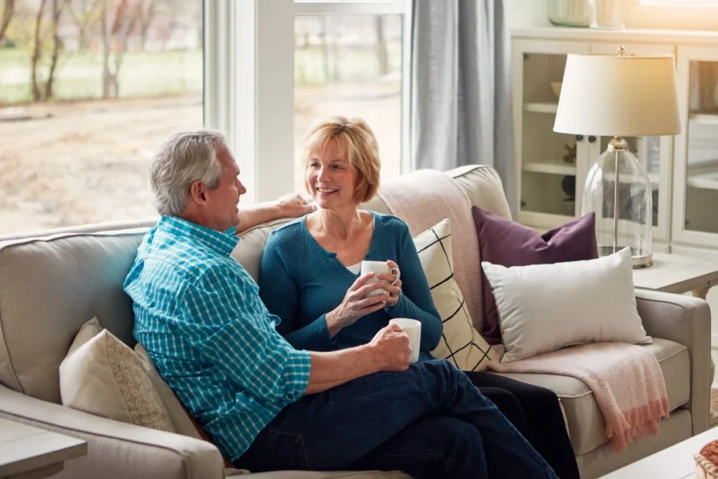 Senior man and woman relaxing on a sofa holding mugs