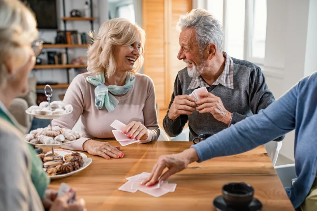 Older adults playing cards around a table with pastries