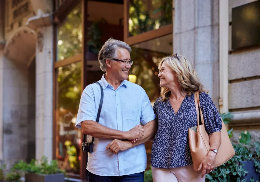 Smiling older couple walking arm in arm past storefronts