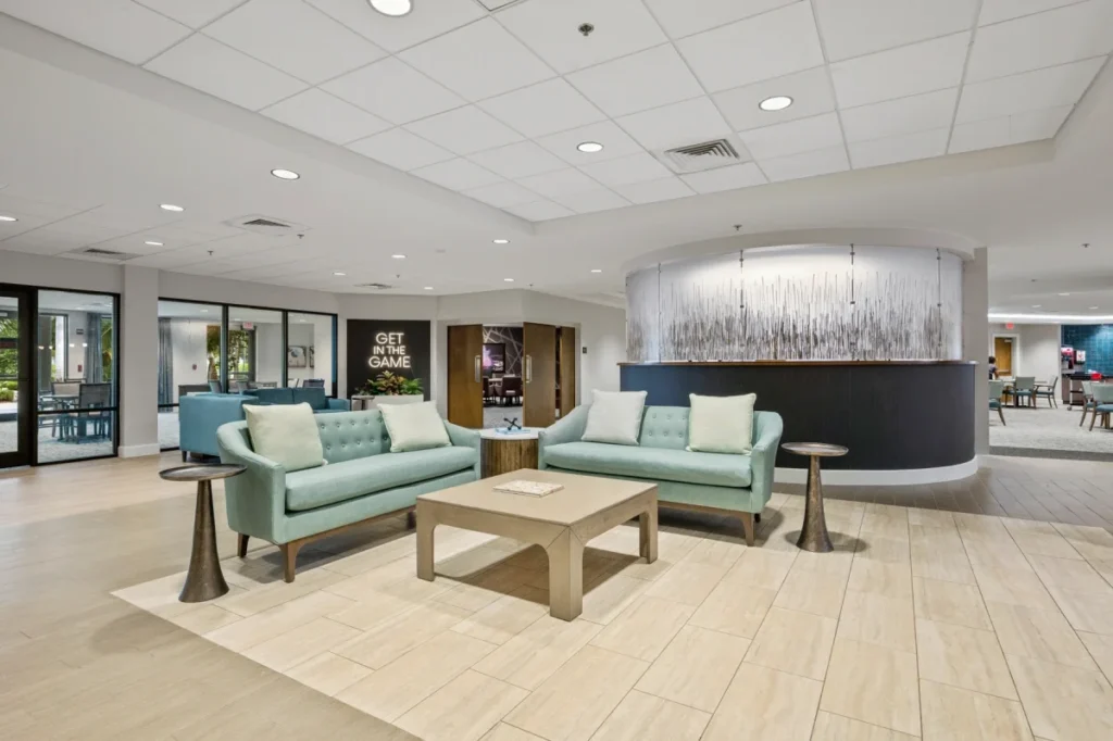 Bright common lounge with teal sofas, a coffee table and a curved feature wall